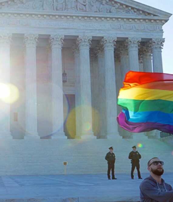 A man waving an LGBTQ flag in front of the Supreme Court