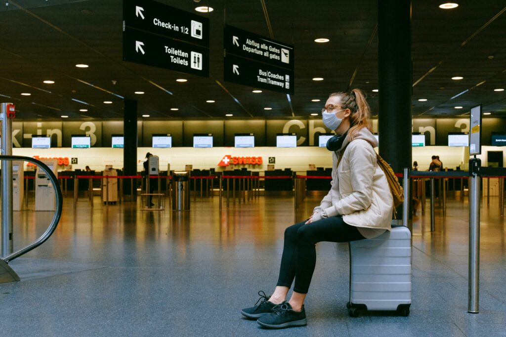 airline passenger sitting on suitcase in terminal - U.S. airline industry starting to recover