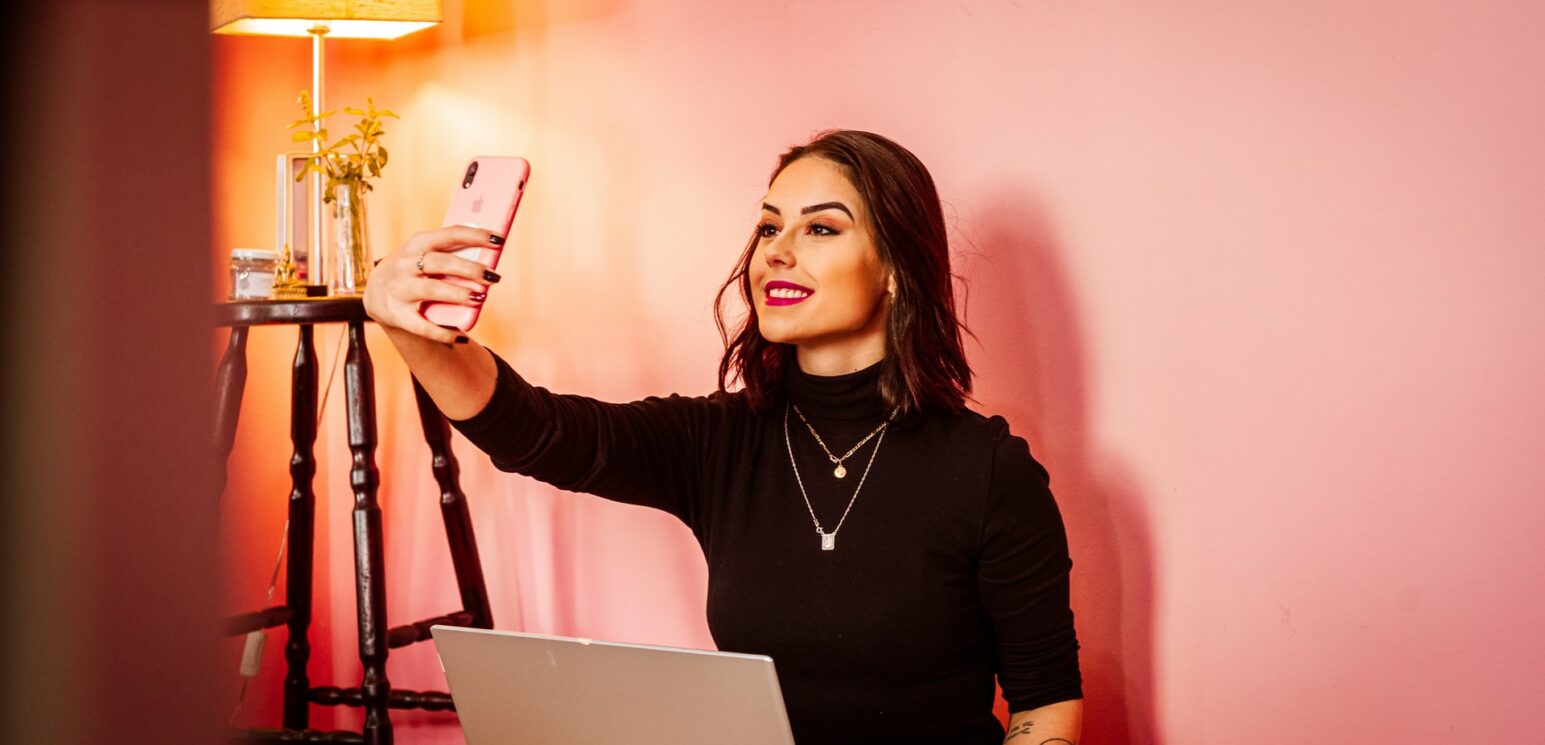 influencer marketing requires proper disclosure - woman takes a selfie against a pink wall